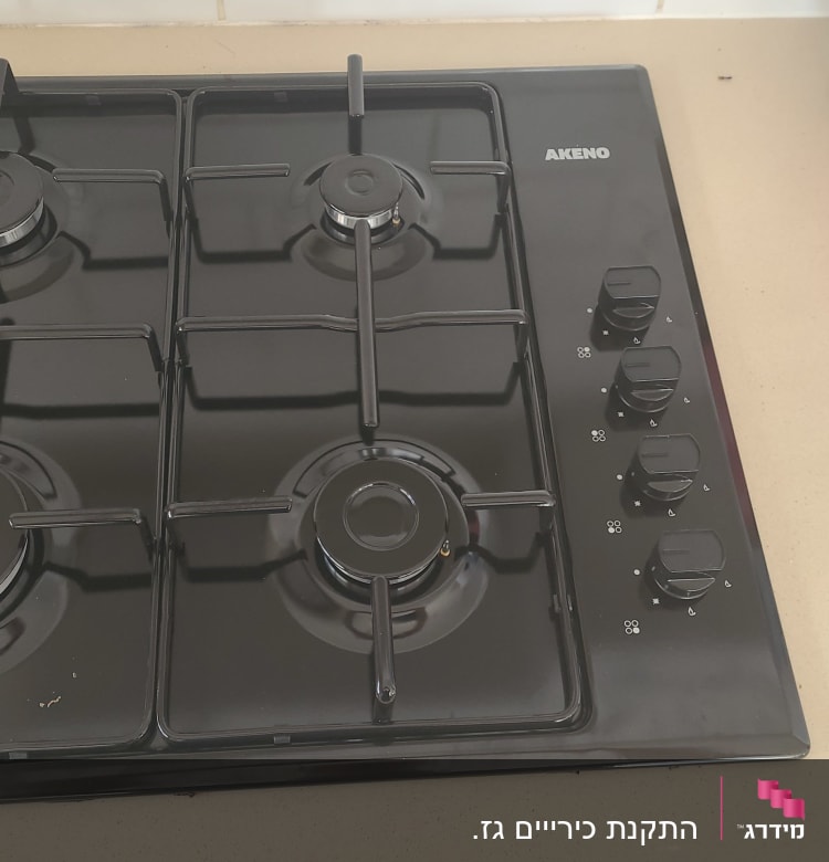 כיריים גז שחורות עם ארבעה מבערים וכפתורי שליטה